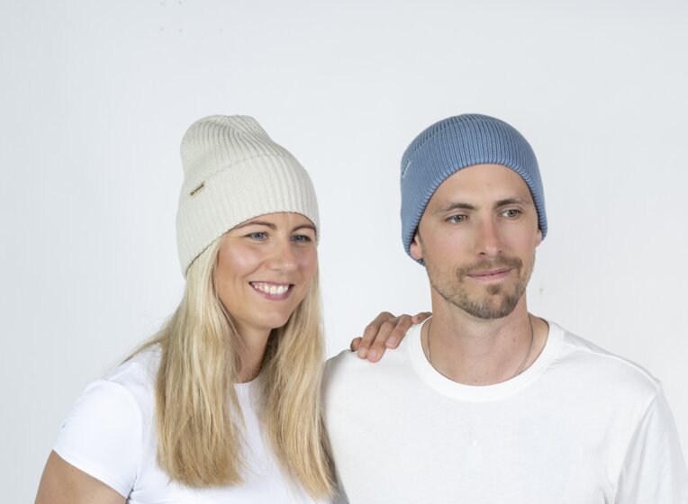 Man and woman wearing Ski amadé beanies pose side by side, bright studio setting | © Ski amadé GmbH / Lorenz Masser
