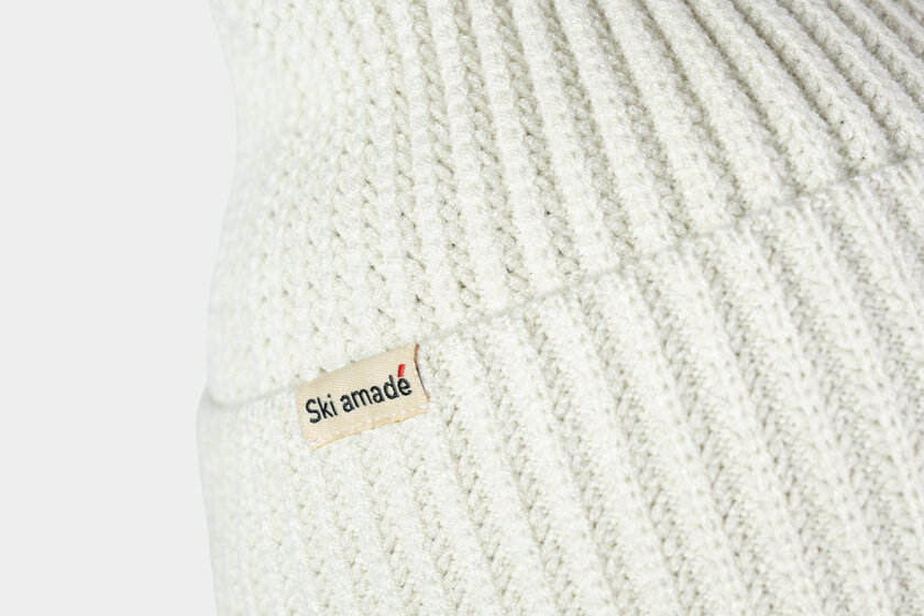 Cremeweiße, strukturierte Strickmütze mit Ski amadé Logo auf einem Stoffetikett | © Ski amadé GmbH / Lorenz Masser