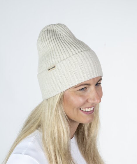 Frau mit cremeweißer Ski amadé Mütze und weißem Shirt vor hellem Hintergrund | © Ski amadé GmbH / Lorenz Masser