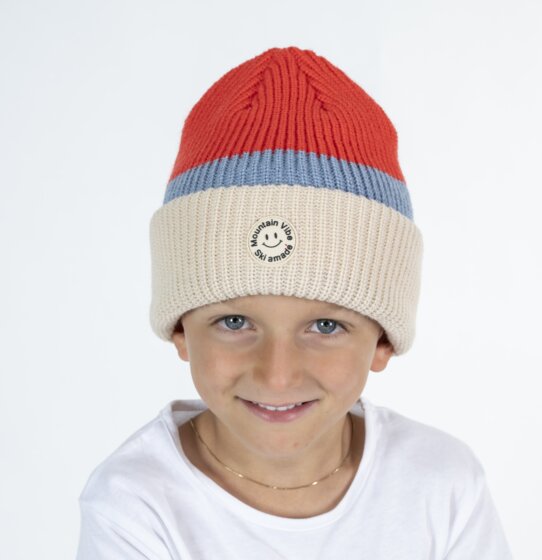 Junge trägt rot-beige Mountain Vibe Ski amadé Mütze und weißes Shirt im Studio | © Ski amadé GmbH / Lorenz Masser