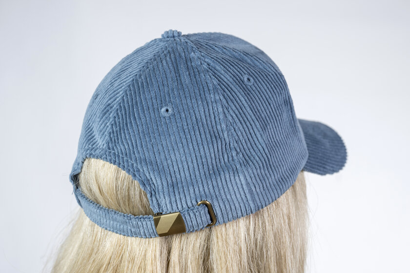 Rückansicht eines blauen Cord-Baseballcaps mit verstellbarem Metallverschluss auf dem Kopf einer blonden Person | © Ski amadé GmbH / Lorenz Masser