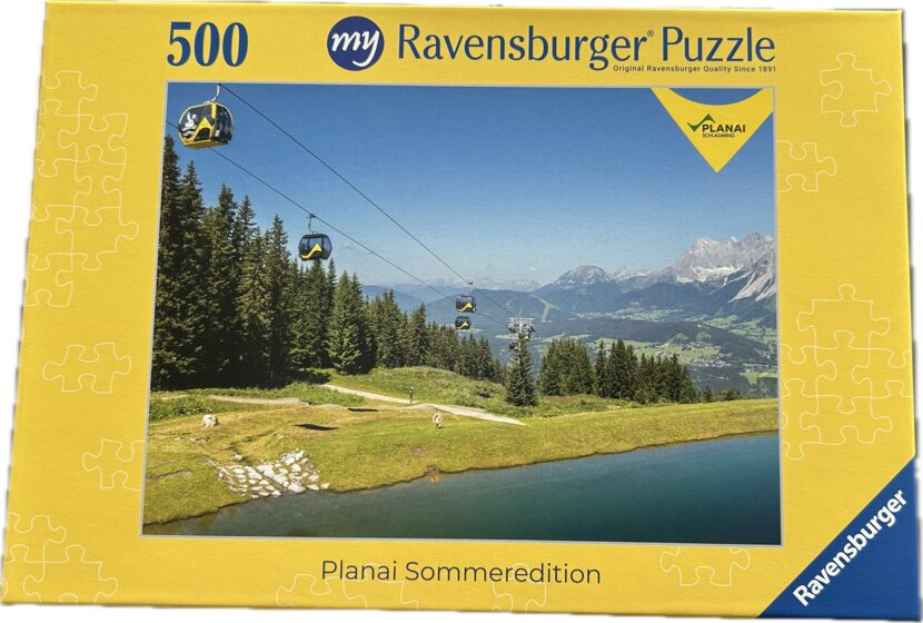 Puzzlebox zeigt Gondelbahn über grüne Wiesen mit Speicherteich, Wald und Alpen im Sommer, 500 Teile | © Planai-Hochwurzen-Bahnen GmbH