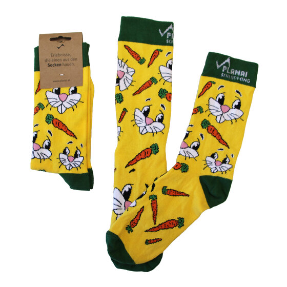 Drei gelbe Kindersocken mit grünem Bündchen, bedruckt mit weißen Hasengesichtern und orangen Karotten auf gelbem Grund | © Planai-Hochwurzen-Bahnen GmbH
