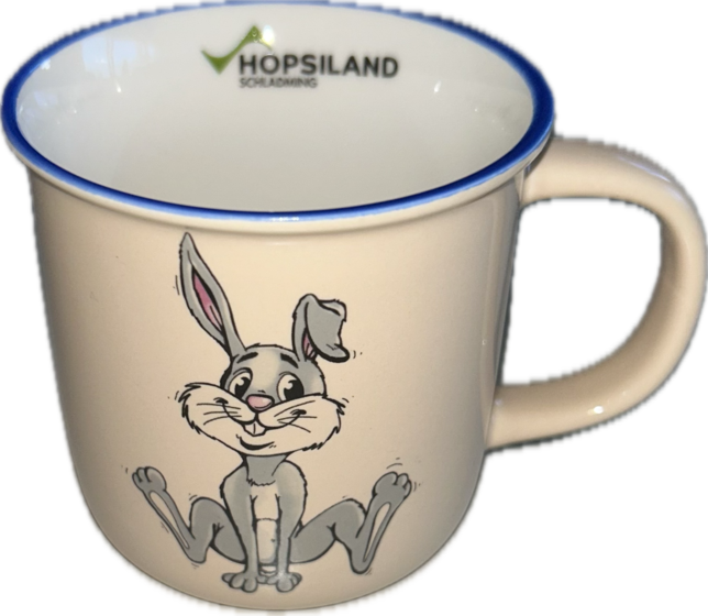 Beigefarbene Kindertasse mit sitzendem Hopsi-Hasen, blauem Rand und Hopsiland-Schriftzug auf der Innenseite | © Planai-Hochwurzen-Bahnen GmbH