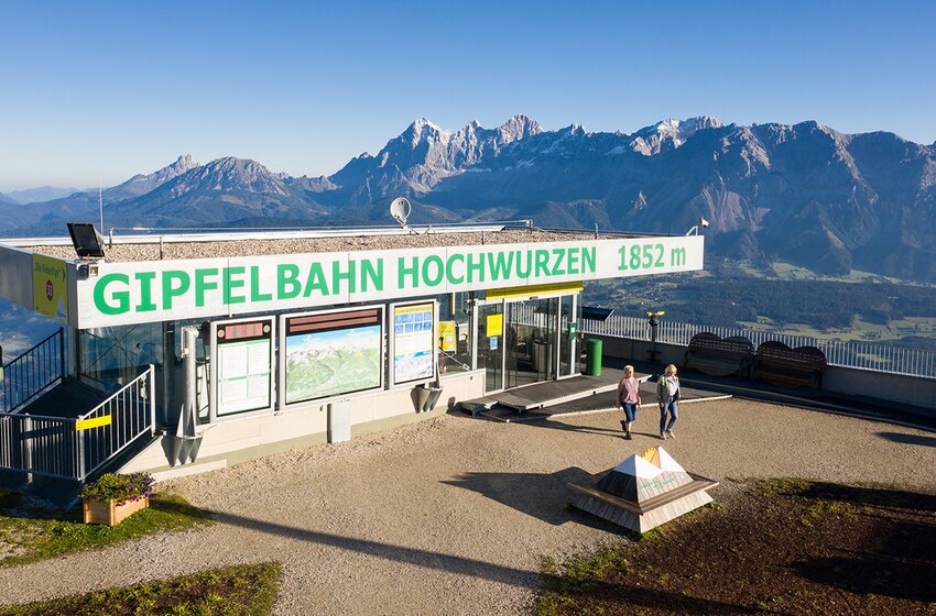 Bergstation der Gipfelbahn Hochwurzen auf 1852 m mit Panoramablick und zwei Wanderern im Morgenlicht | © Planai-Hochwurzen-Bahnen GmbH