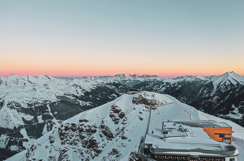 Panorama des verschneiten Stubnerkogels bei Sonnenaufgang mit Seilbahnstation und Blick auf die Alpen. | © Gasteiner Bergbahnen AG