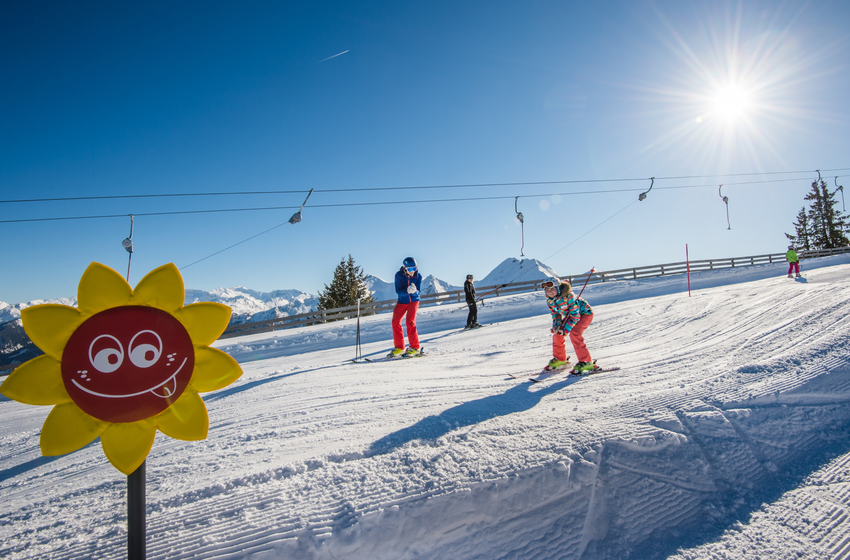Kind fährt auf Funslope mit bunter Sonne als Markierung bei Sonnenschein und Blick auf die Berge. | © Tourismusverband Großarltal