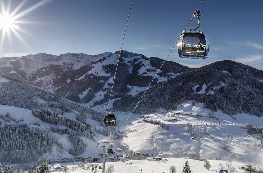 Gondeln der Sonnbergbahn schweben bei Sonnenschein über verschneite Hügel im Skigebiet Hochkönig. | © Hochkönig Bergbahnen GmbH