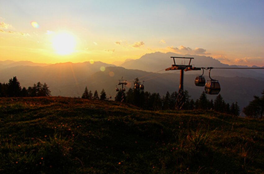 Gondelbahn fährt am Geisterberg über herbstliche Wiesen bei Sonnenaufgang mit Blick auf Bergsilhouetten und goldenen Himmel. | © Snow Space Salzburg Bergbahnen