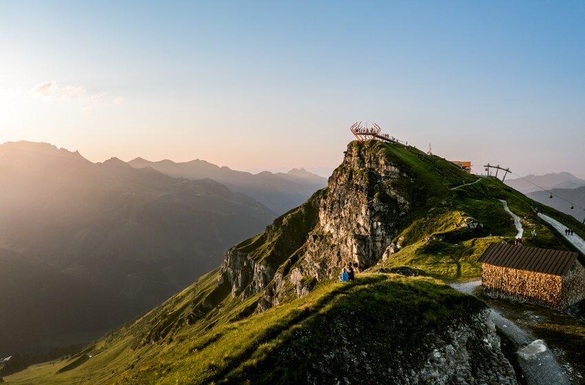 Aussichtsplattform auf felsigem Bergkamm mit Wanderweg, Hütte und Blick auf umliegende Berge im Abendlicht | © Gasteiner Bergbahnen AG