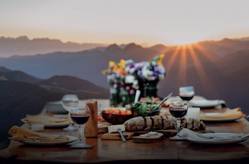 Festlich gedeckter Tisch mit Brot, Wein und Blumen vor Sonnenuntergang in den Bergen – stimmungsvolle Atmosphäre | © Zauchensee Liftgesellschaft Benedikt Scheffer GmbH